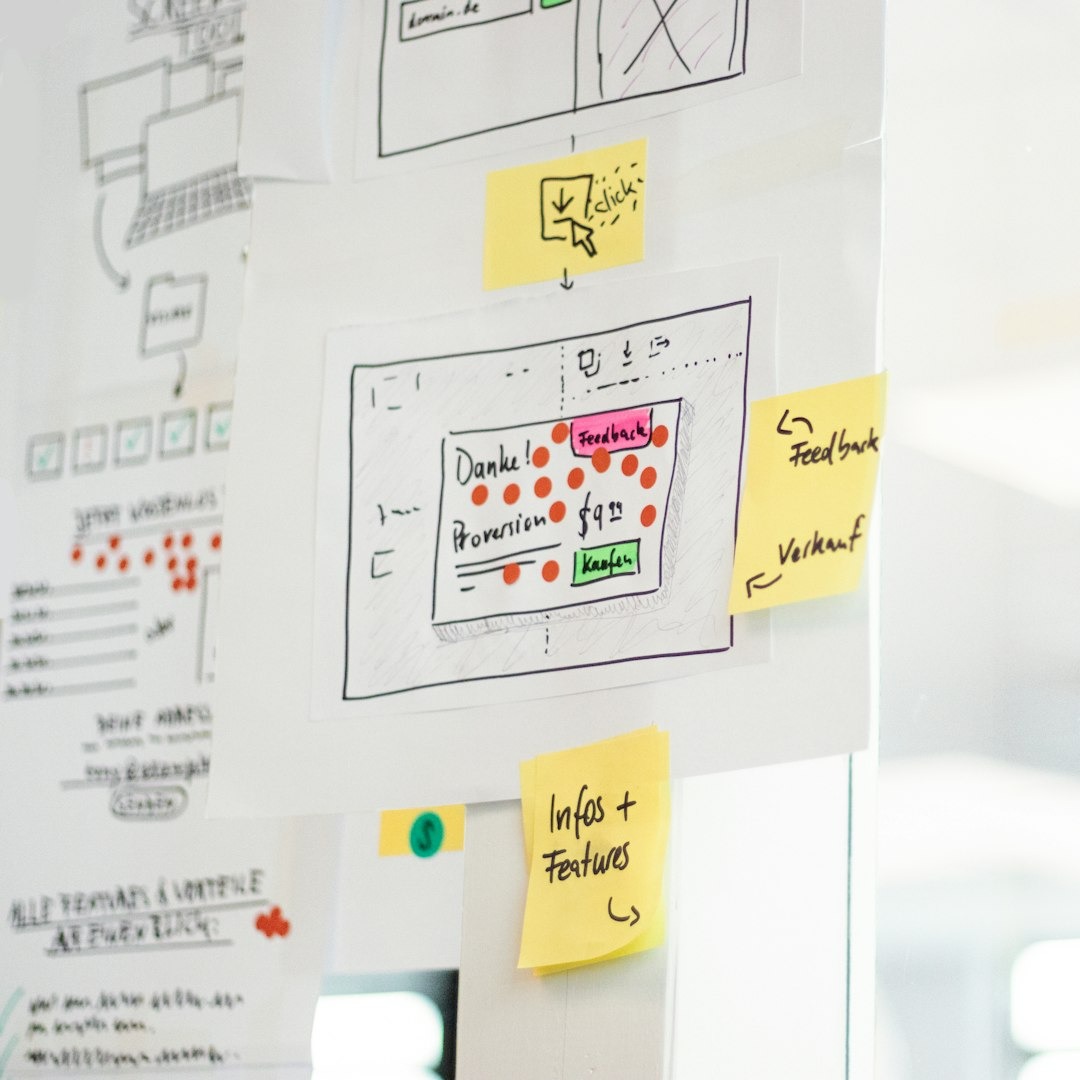 Hand-drawn website wireframes with sticky notes on paper.